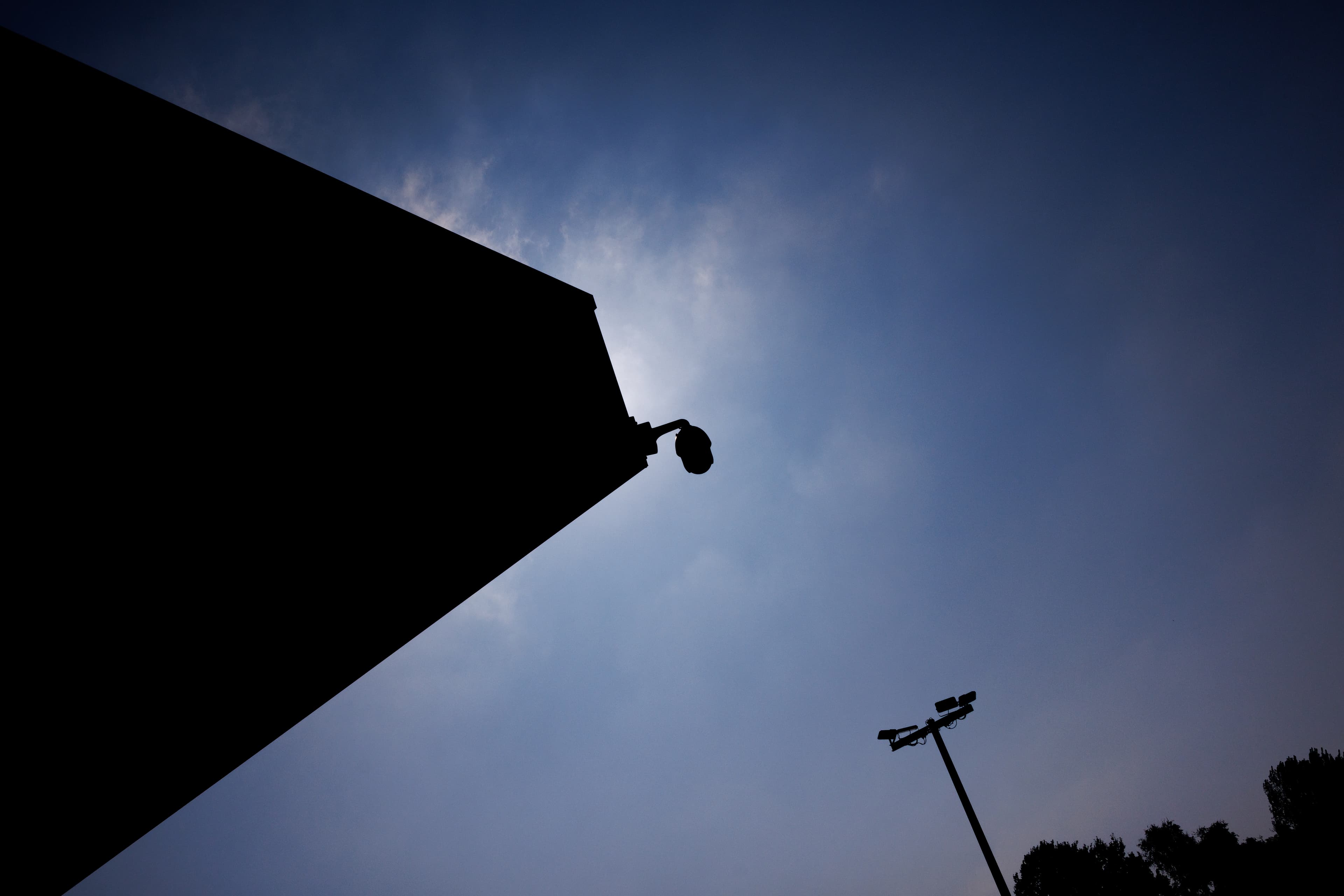 Silhouet van een aantal beveiligingscamera's tegen een blauwe lucht.